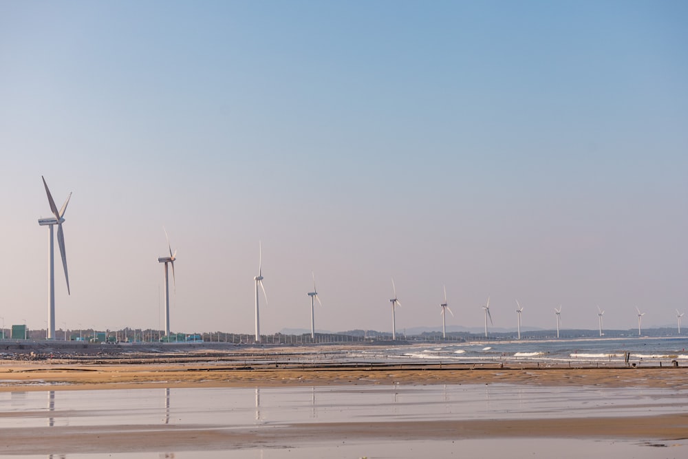 a group of windmills on a beach next to the ocean