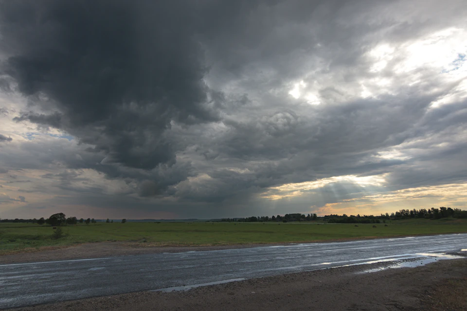 Serene rural landscape under an overcast sky with a winding road stretching into distance