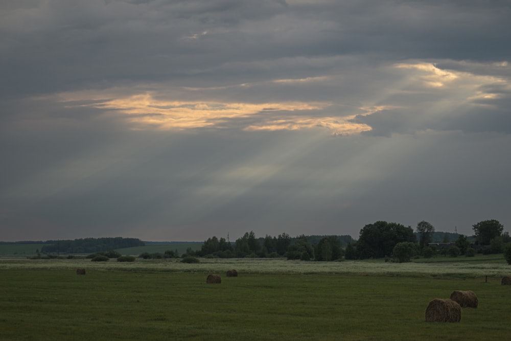 a field with hay bales under a cloudy sky