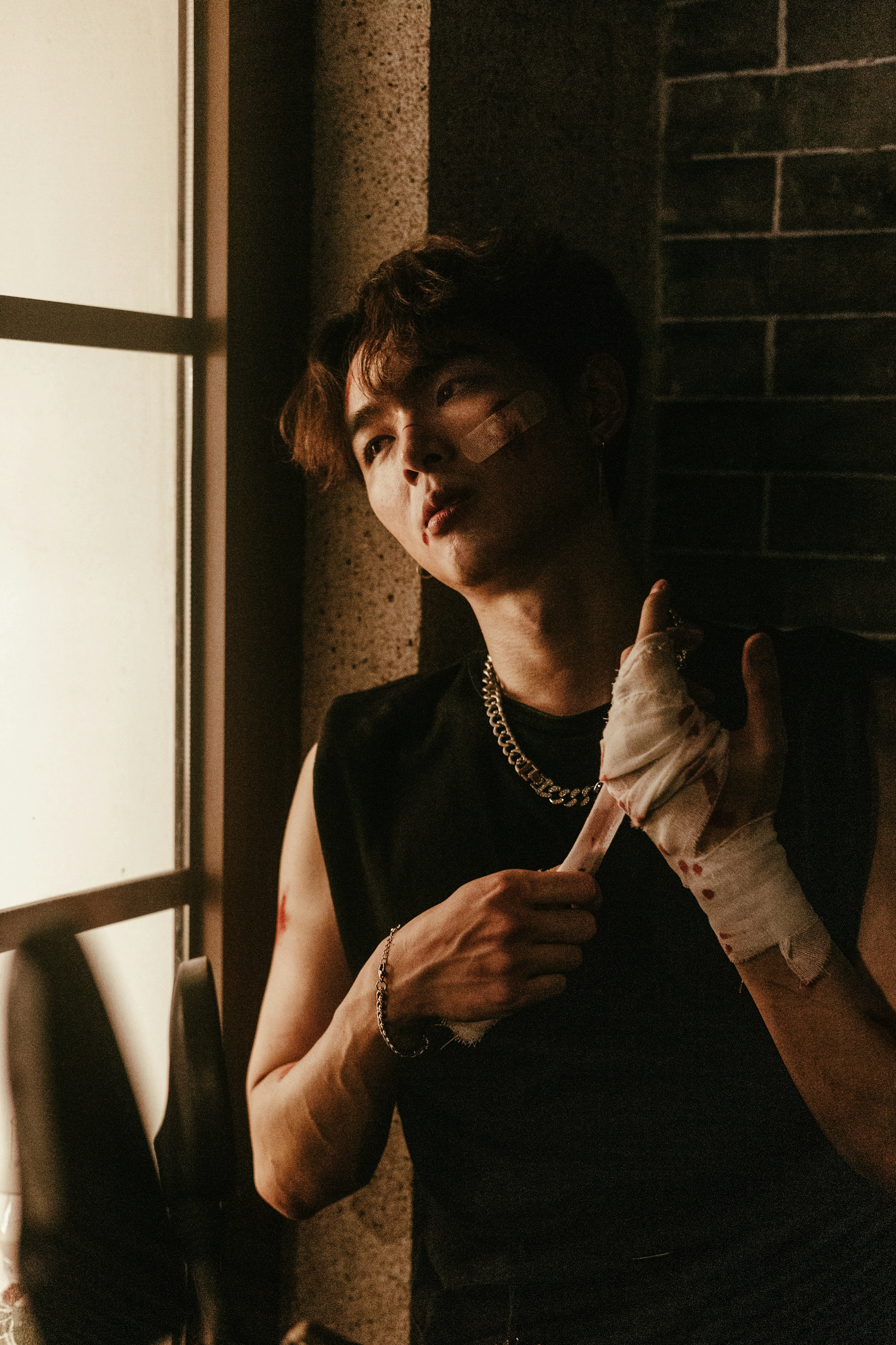 Ein Mann mit Bandagen am Arm steht neben einem Fenster