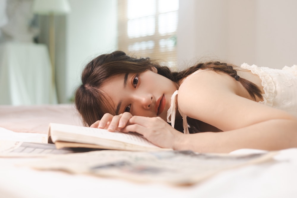 a woman laying on a bed reading a book