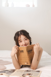 a woman laying on top of a bed holding a book