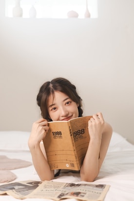 a woman laying on top of a bed holding a book