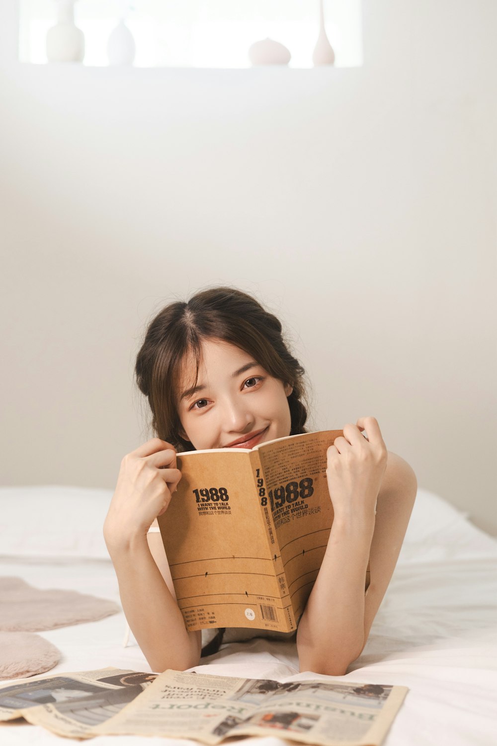 a woman laying on top of a bed holding a book