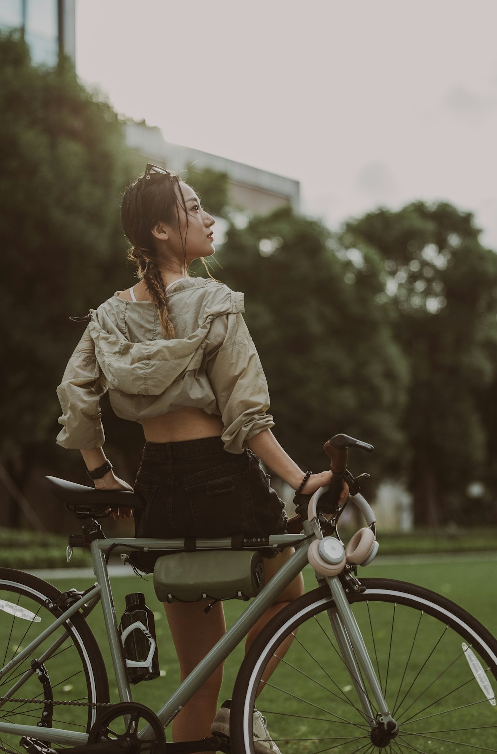 a woman standing next to a bike in a park