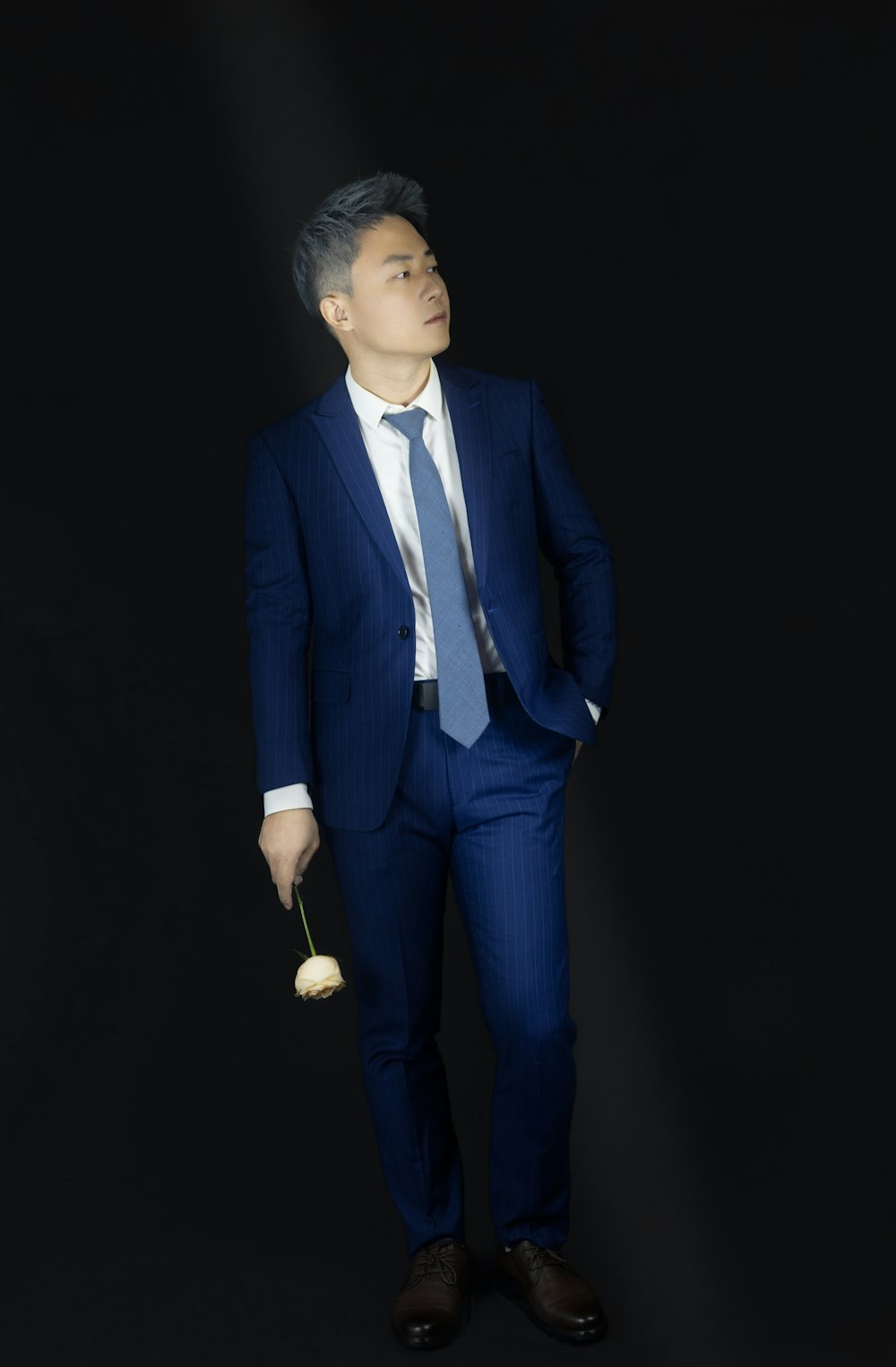 a man in a suit and tie holding a rose