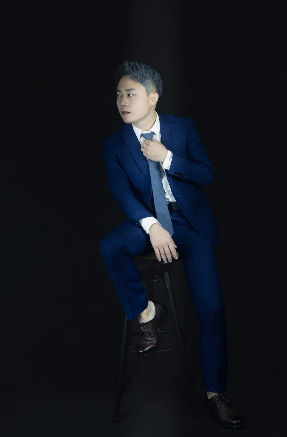 a man in a suit sitting on a stool