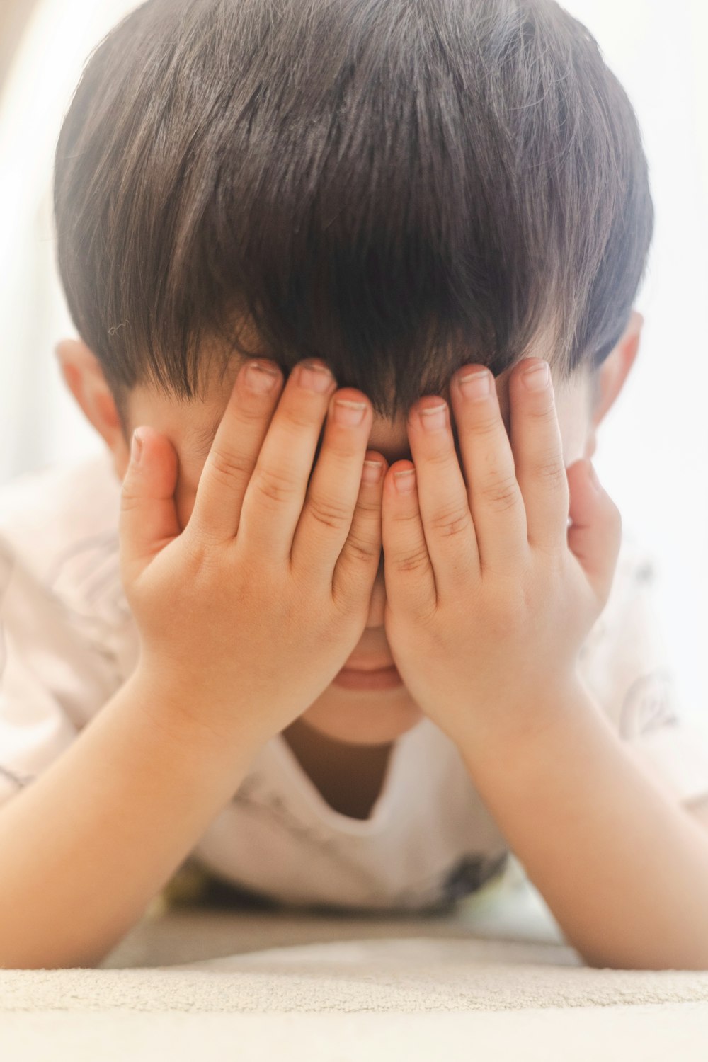 a young boy covering his eyes with his hands