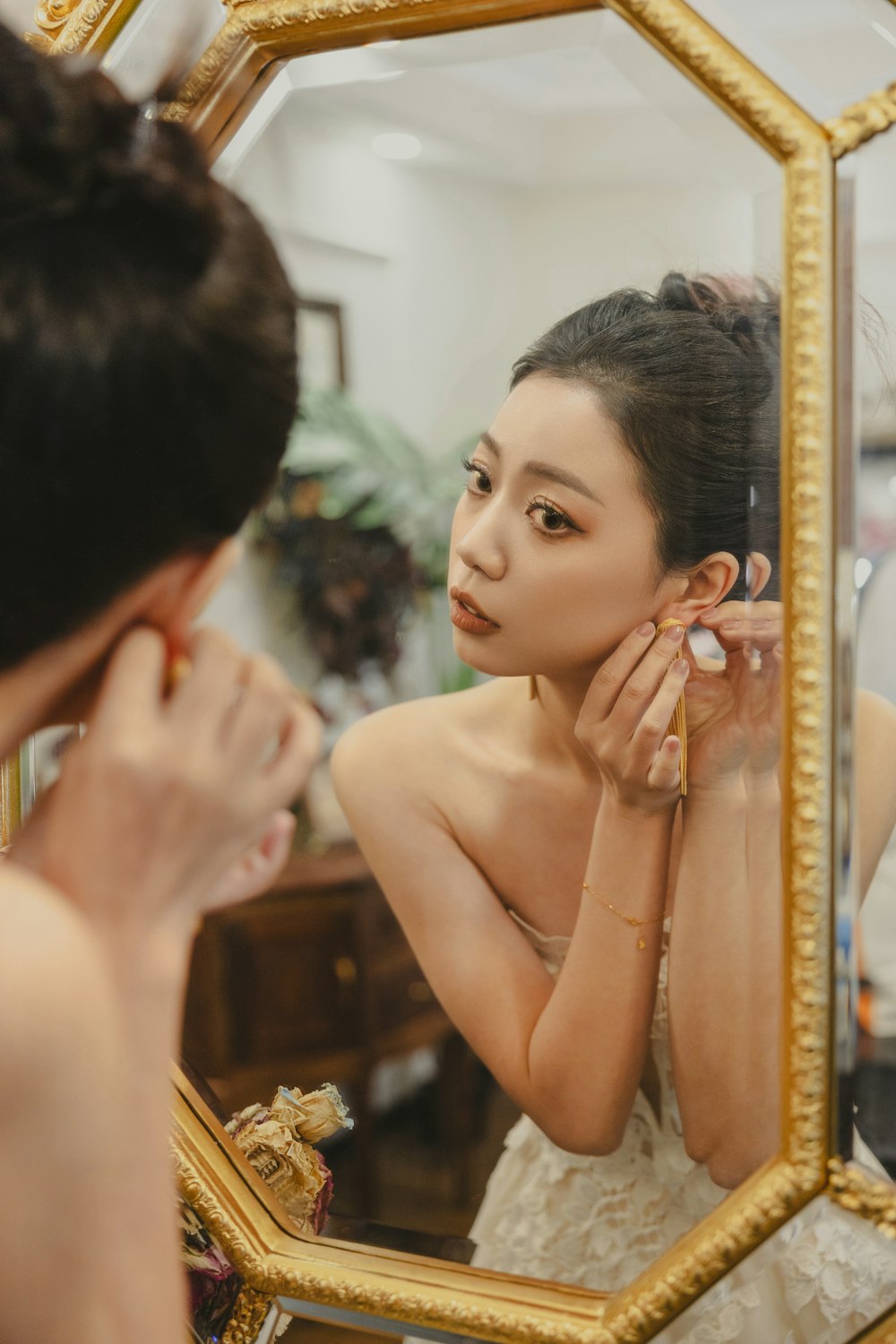 a woman in a white dress is looking at her reflection in a mirror