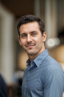a man in a blue shirt smiling at the camera