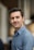 a man in a blue shirt smiling at the camera