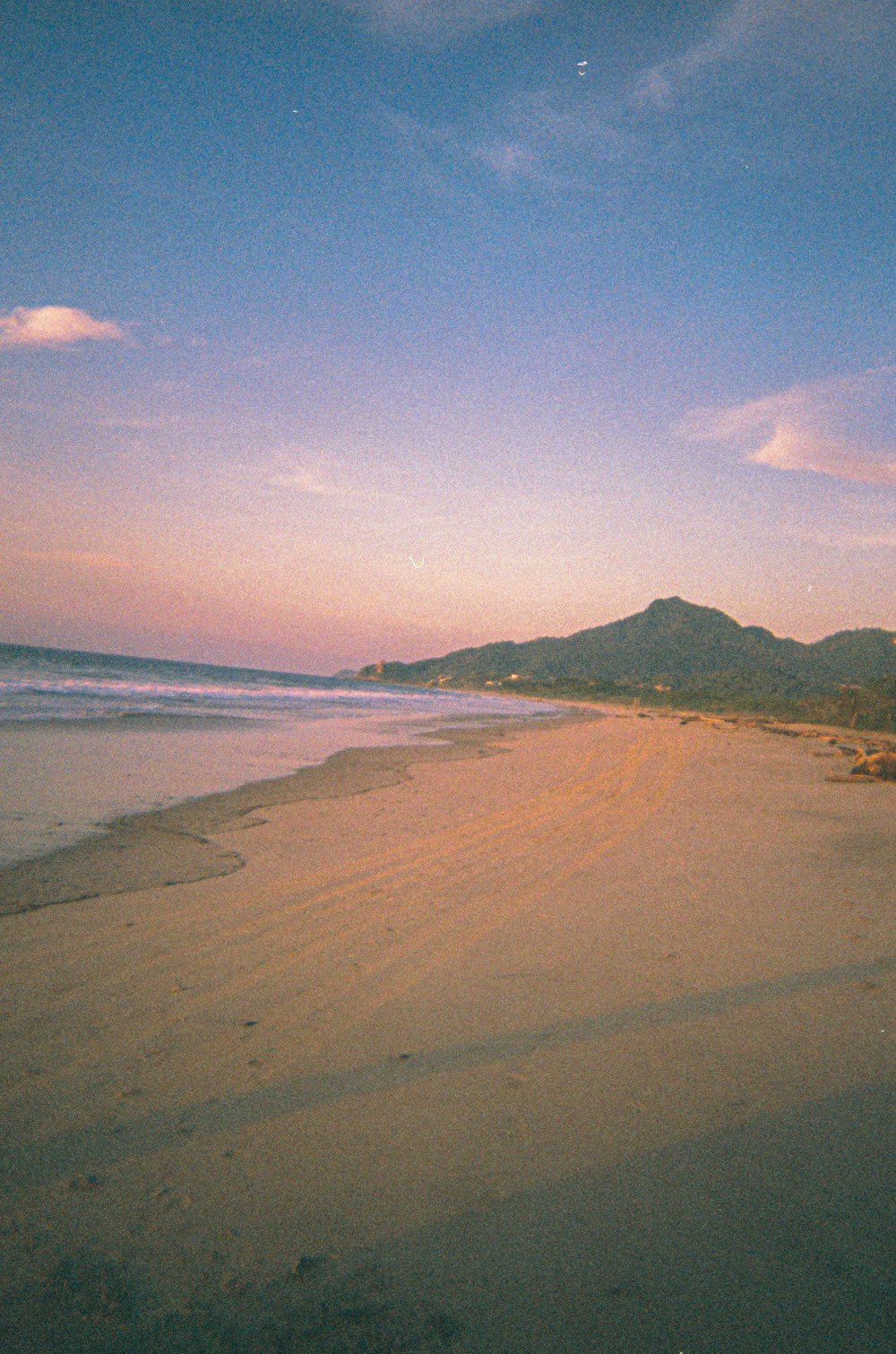 a sandy beach with mountains in the distance