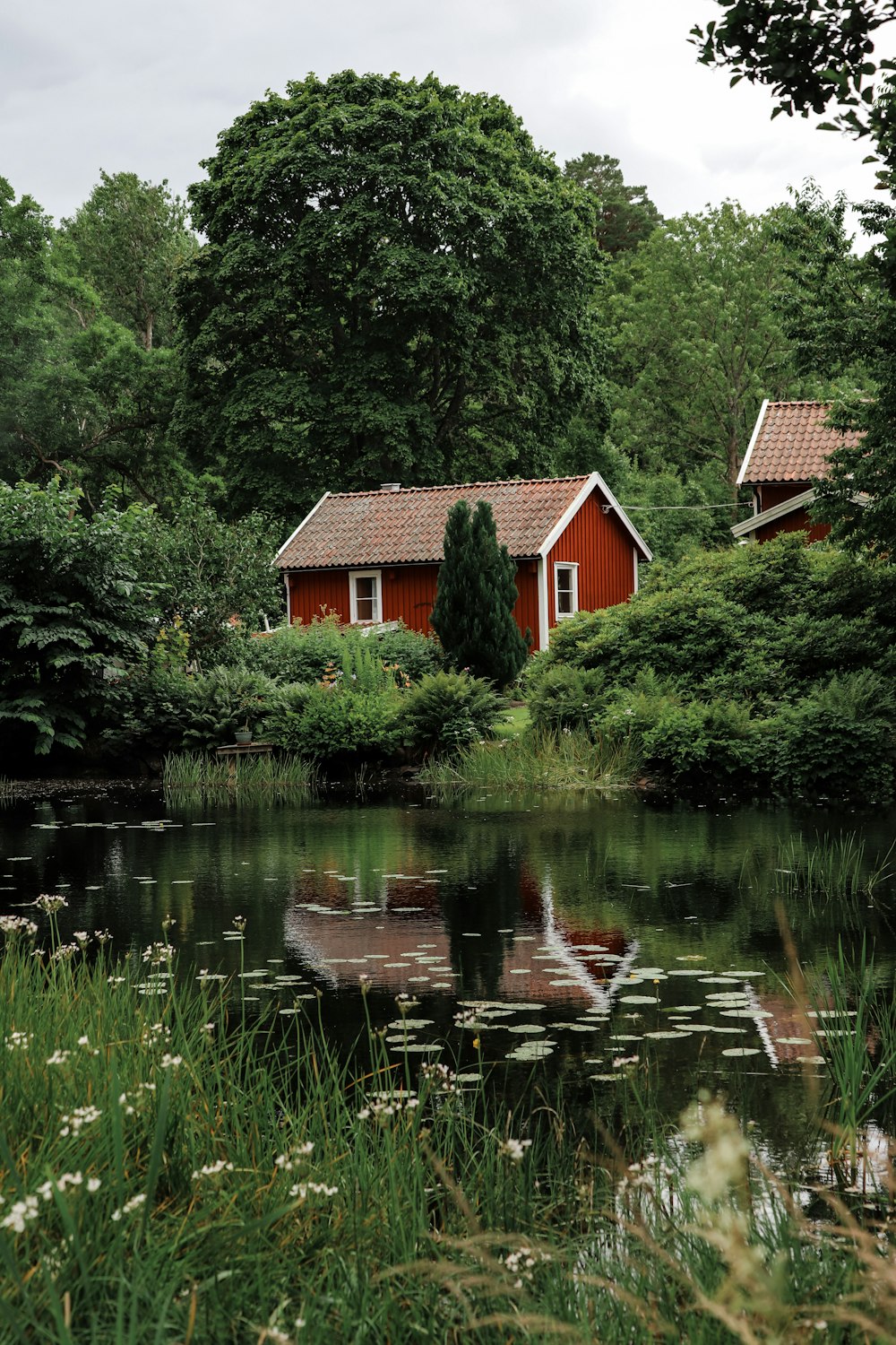 a red house sitting on top of a lush green field