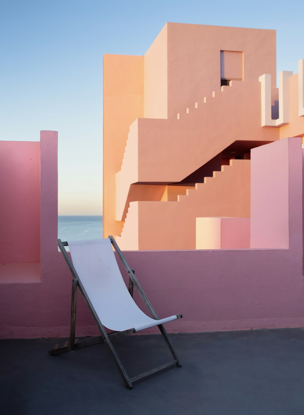a white chair sitting in front of a pink building
