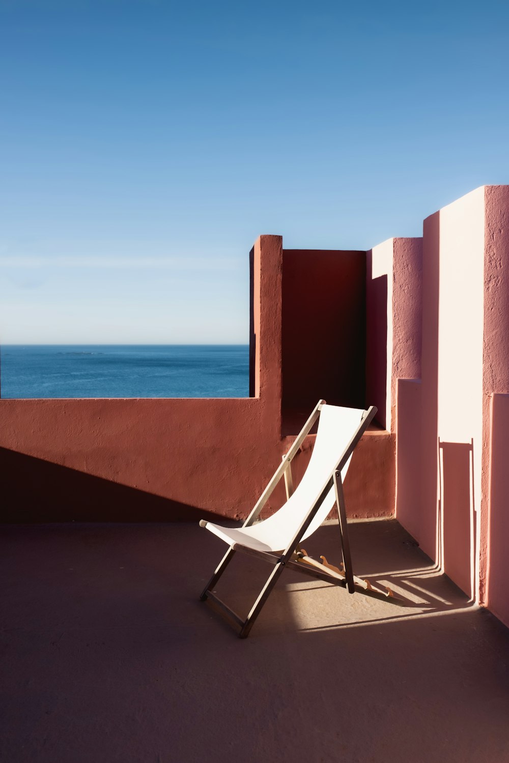 a white chair sitting on top of a balcony next to the ocean
