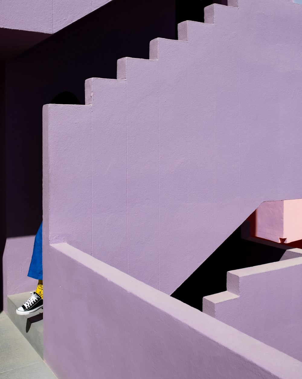 a person sitting on a bench in front of a purple building