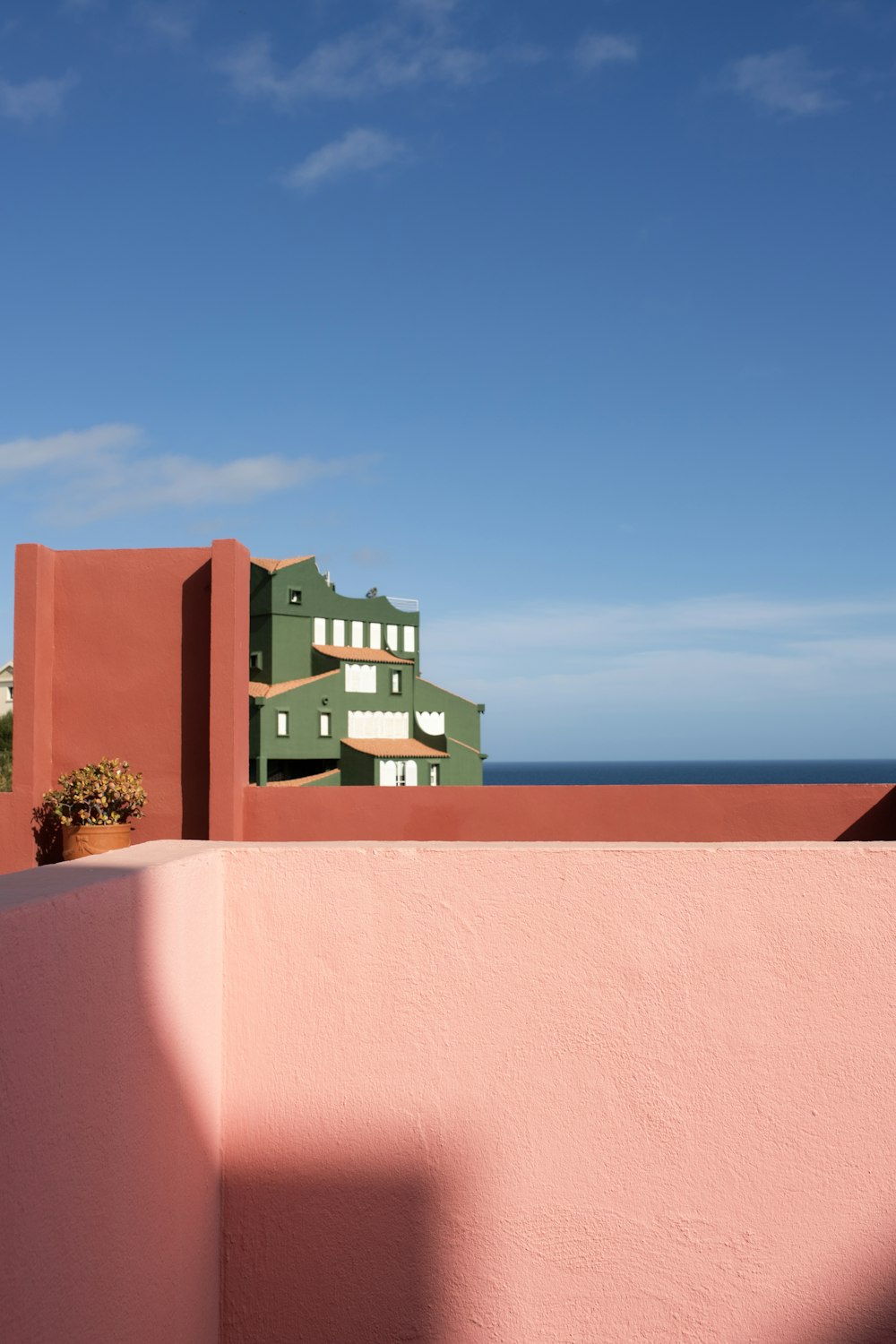 a pink wall with a green building in the background