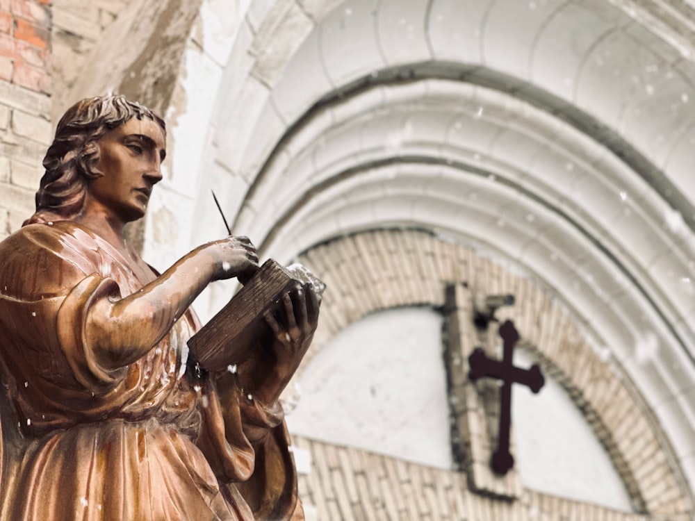 eine Statue einer Frau, die ein Buch vor einer Kirche hält
