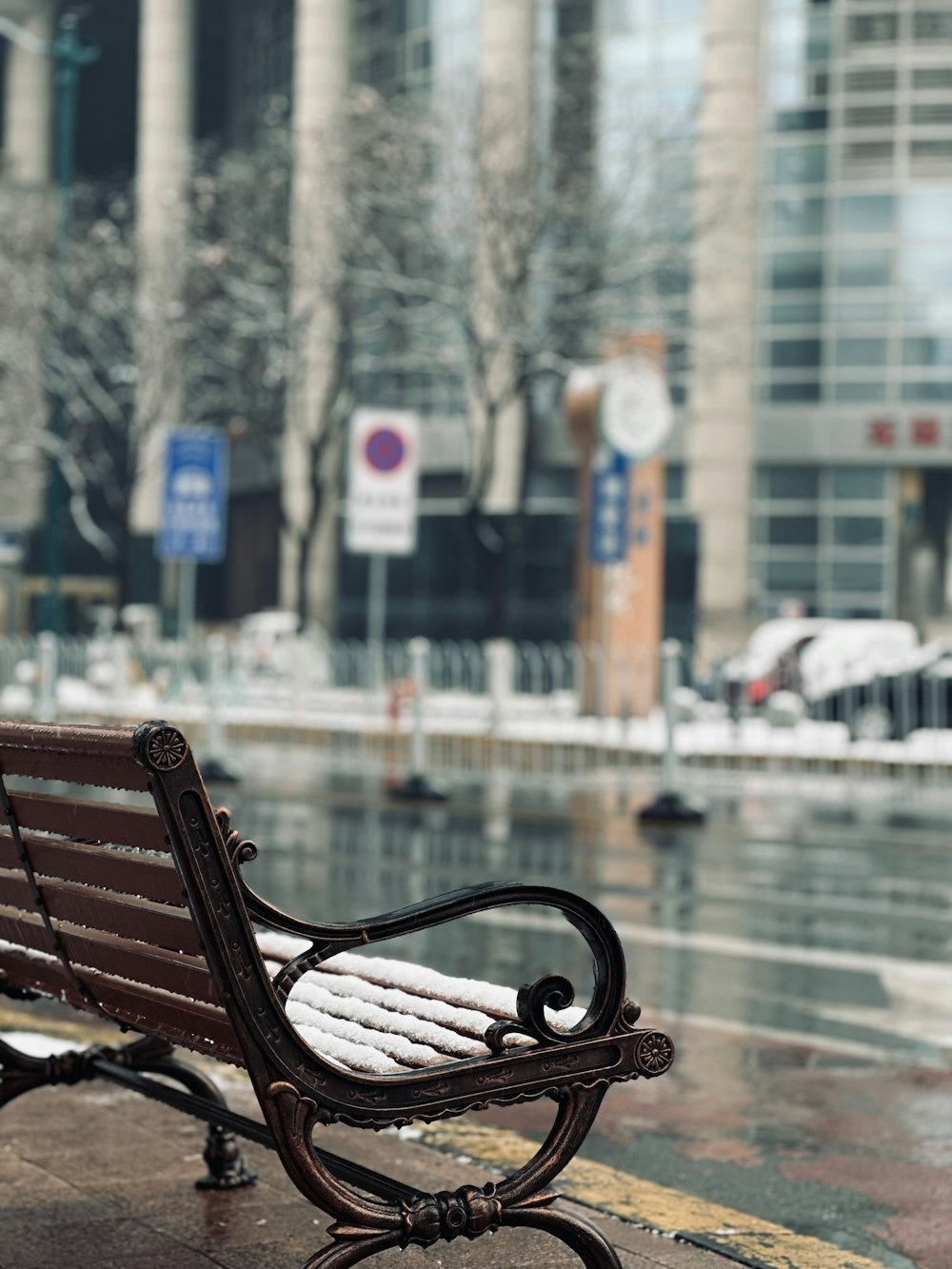 a bench sitting on the side of a road in the rain