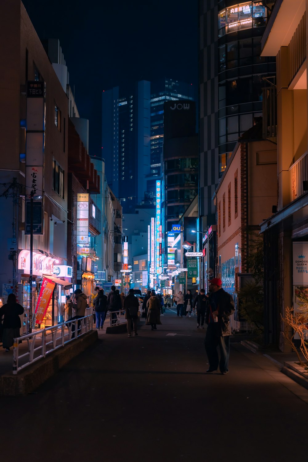 a group of people walking down a street at night