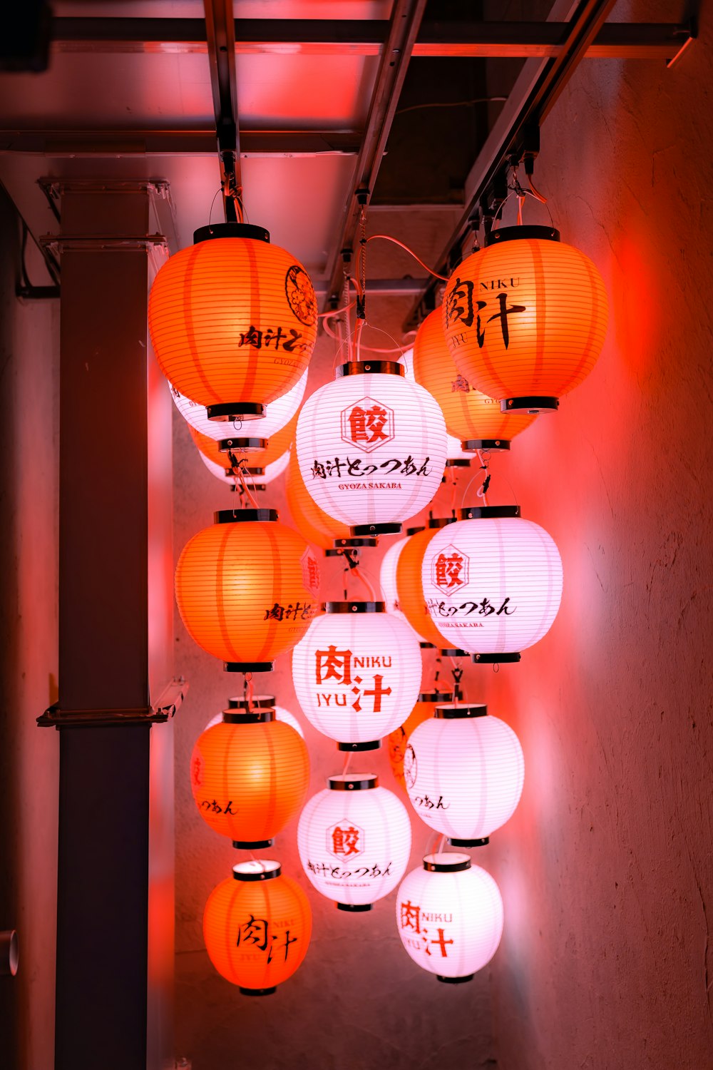 a bunch of orange lanterns hanging from a ceiling