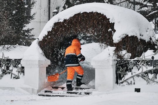 a man in an orange jacket is shoveling snow