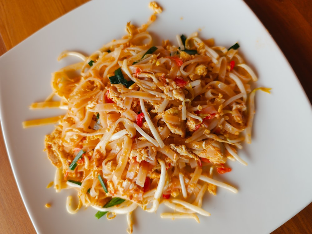 a white plate topped with noodles and vegetables