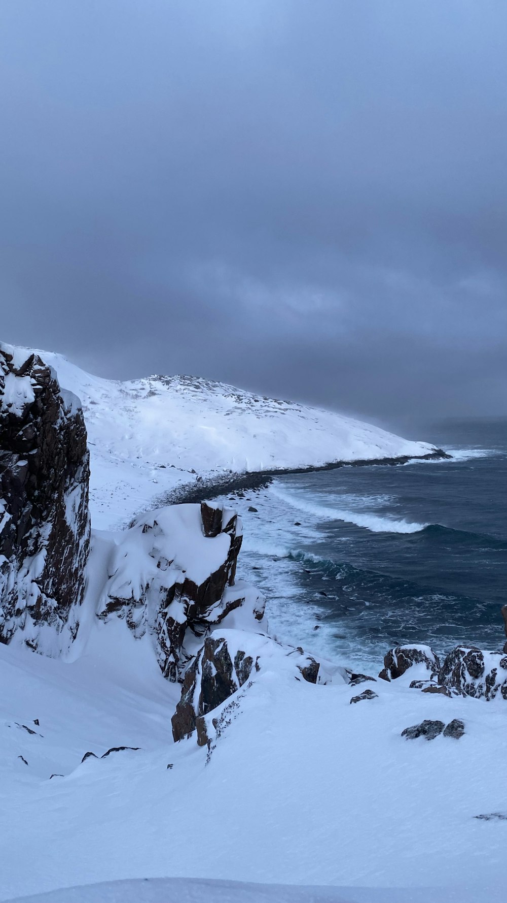 a person standing on a snow covered hill next to a body of water