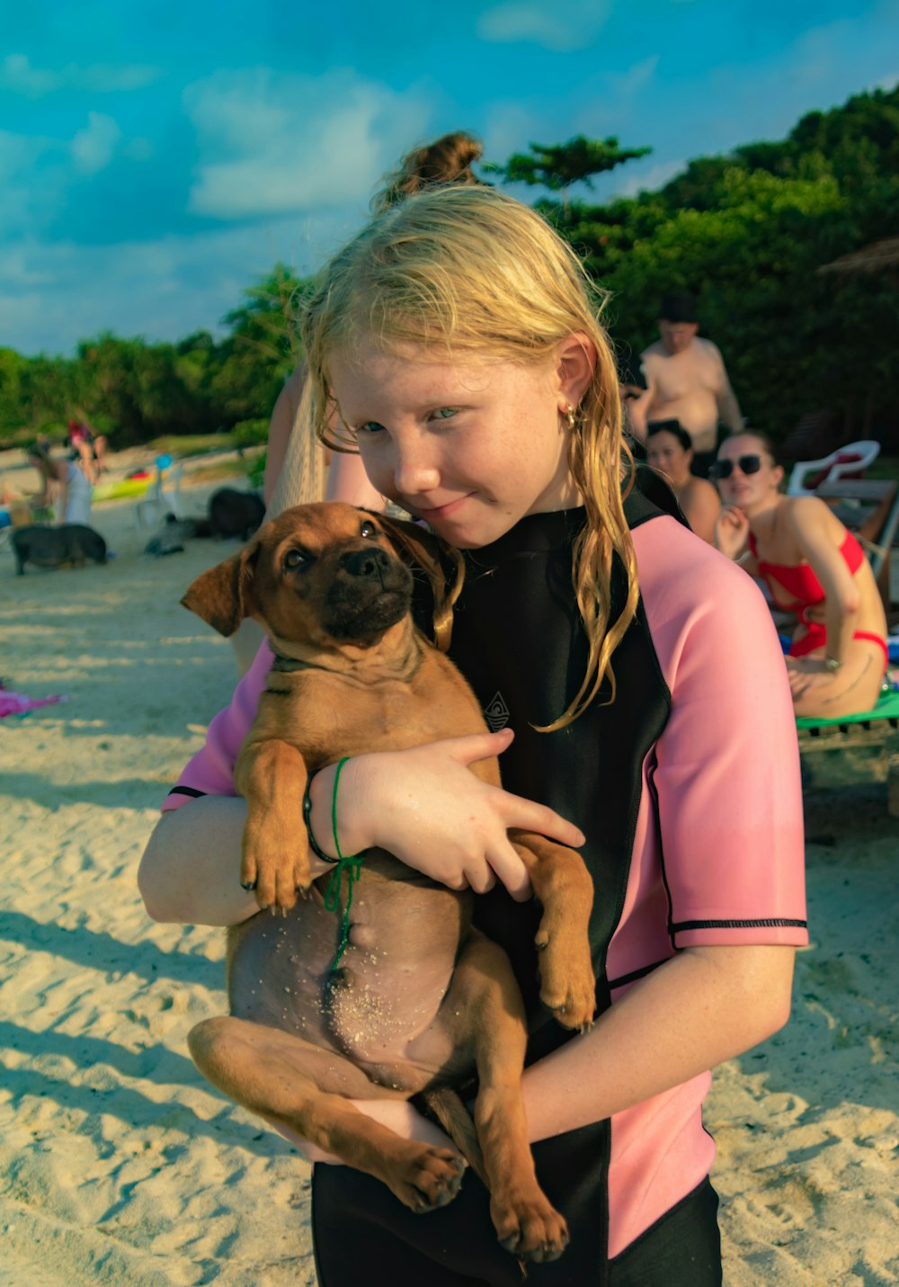 a young girl holding a dog on a beach