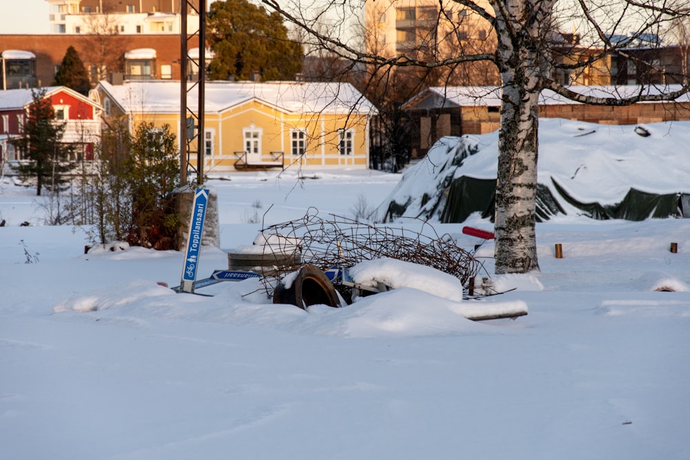 a snow covered area with a few trees and buildings in the background
