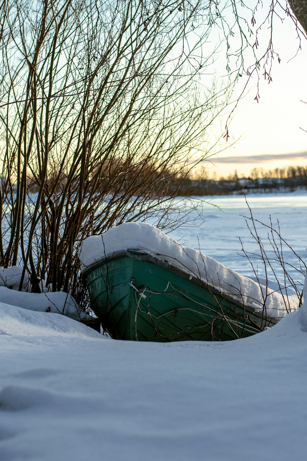 a green boat sitting on top of snow covered ground