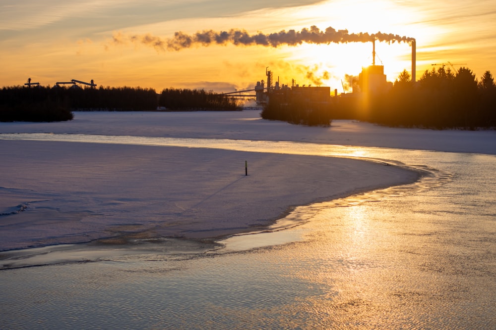 the sun is setting over a frozen river