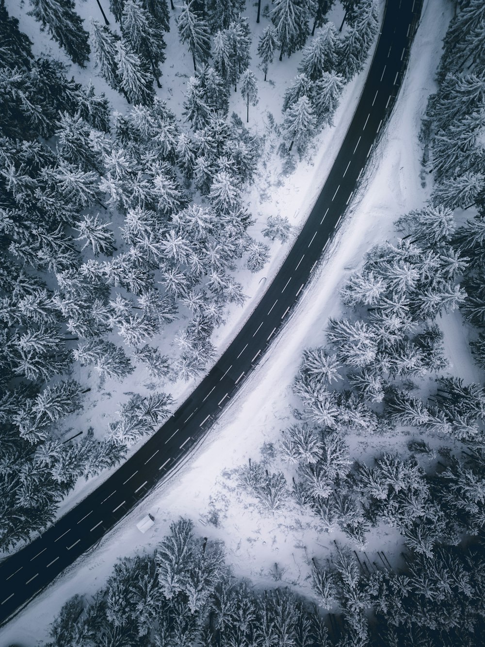 an aerial view of a road in the middle of a snow covered forest