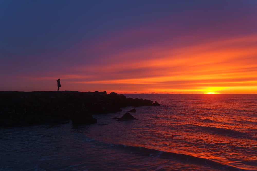 a person standing on the edge of a cliff at sunset