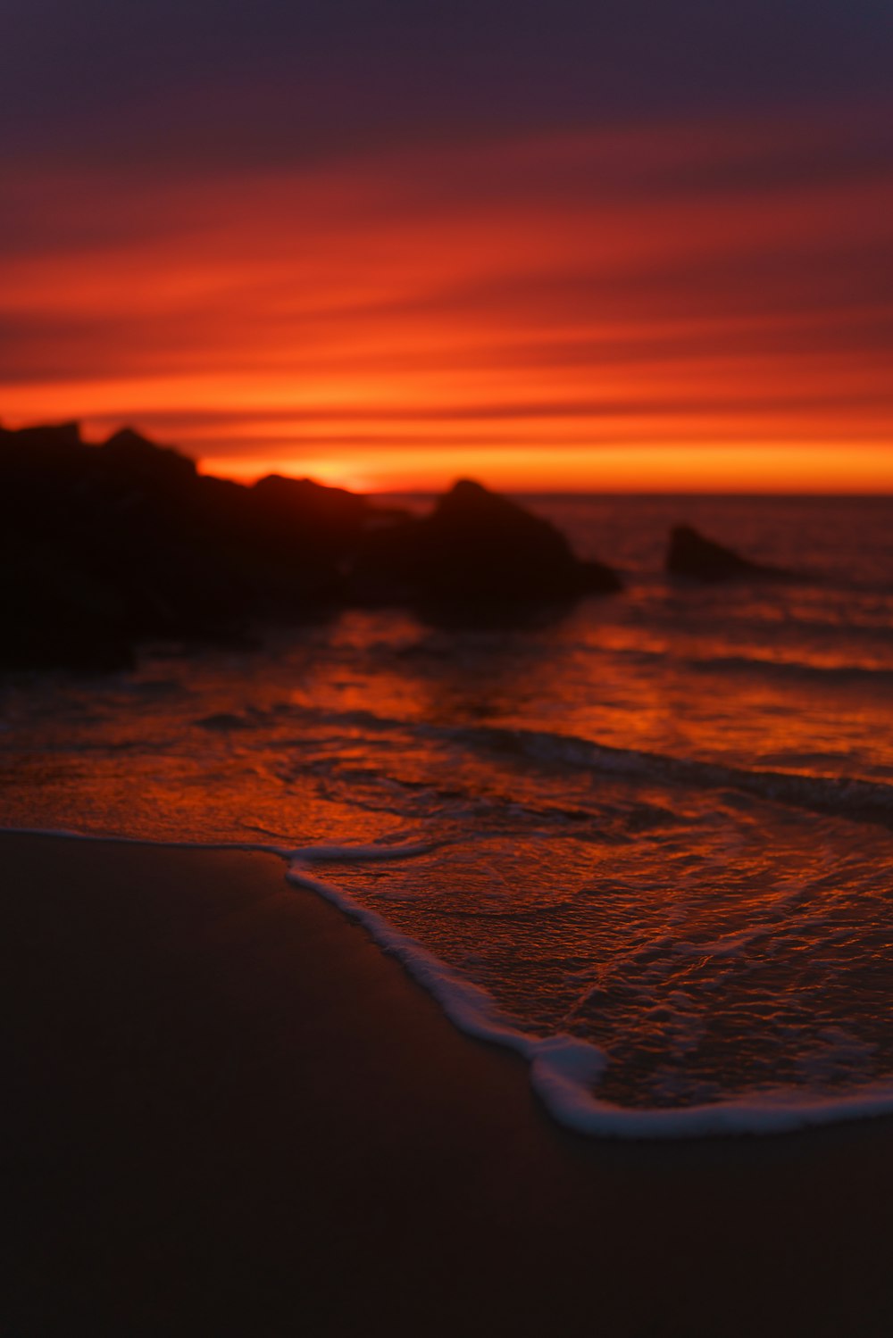 the sun is setting over the water at the beach