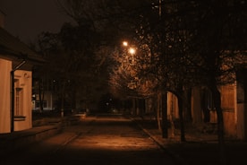 a dark street at night with a street light in the distance
