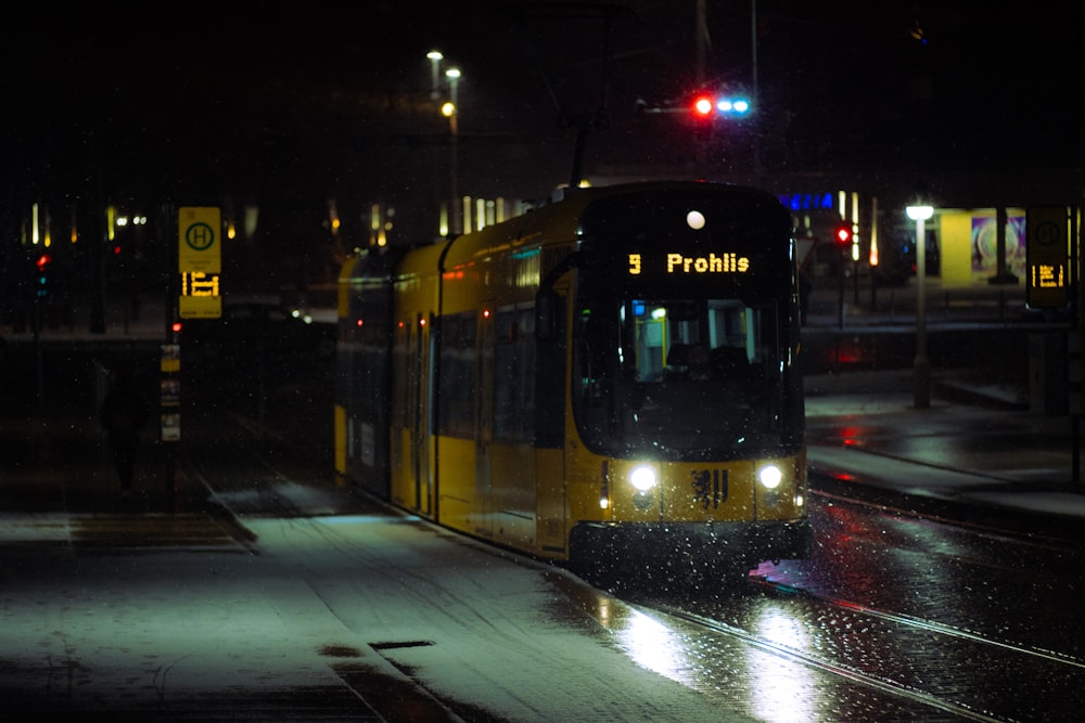 a yellow and black bus on a city street at night