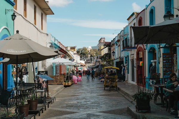 A group of people walking down a street next to buildings — San Cristóbal de las Casas, Mexico