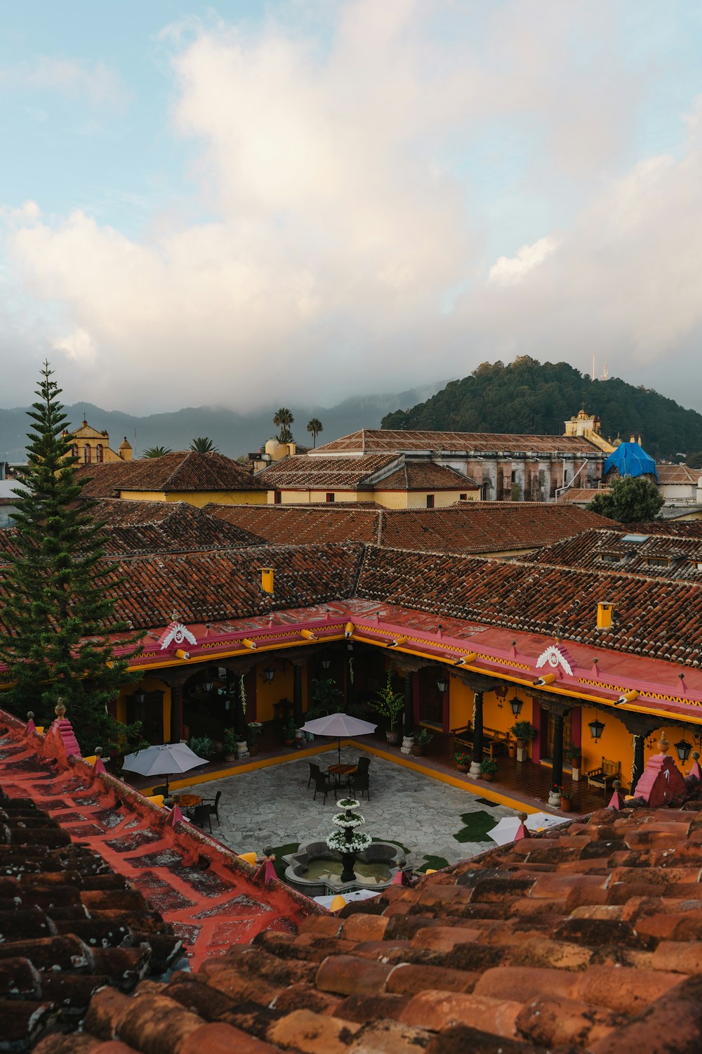 a view of a courtyard with umbrellas and a mountain in the background