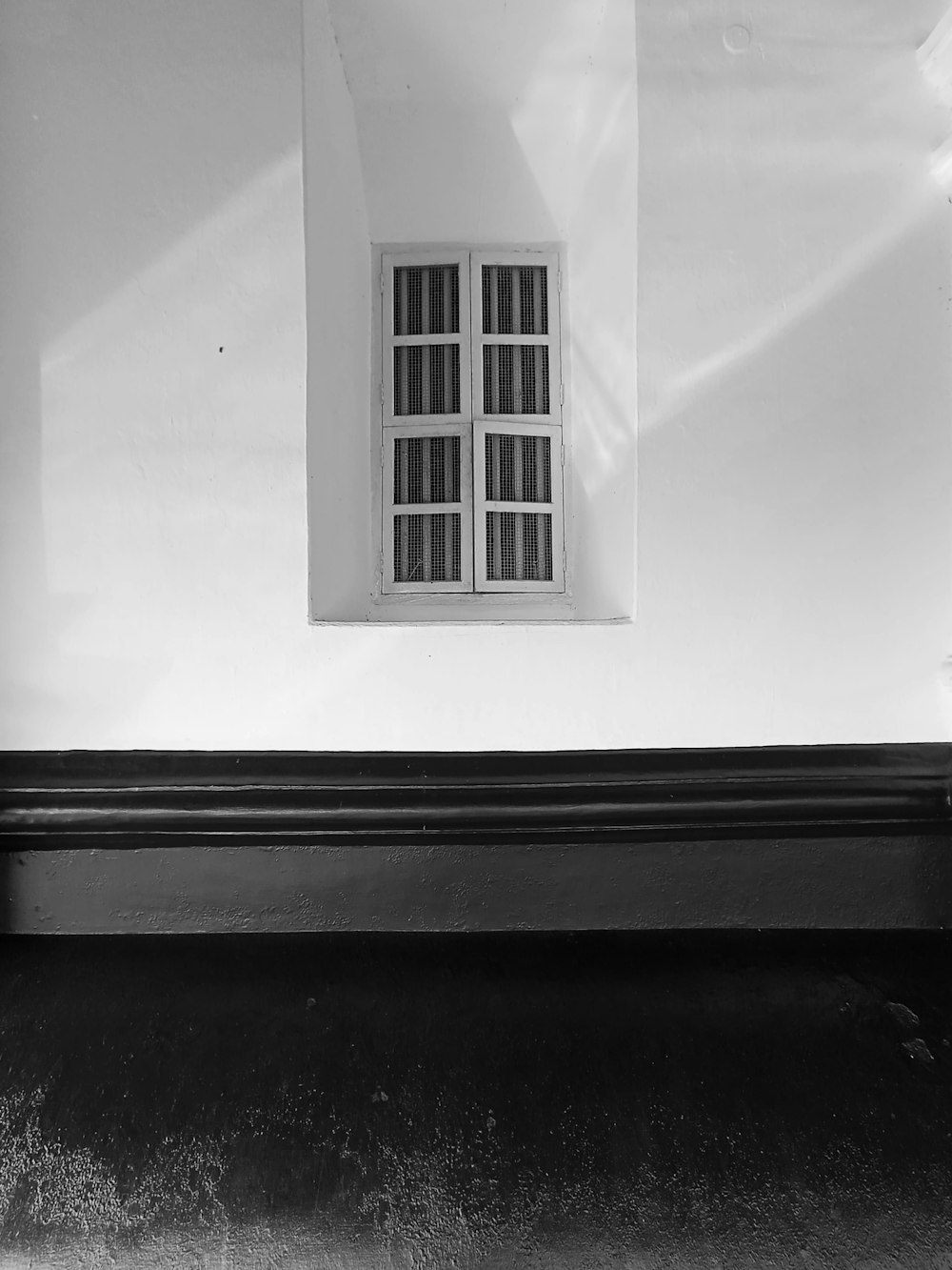 a black and white photo of a window and a bench