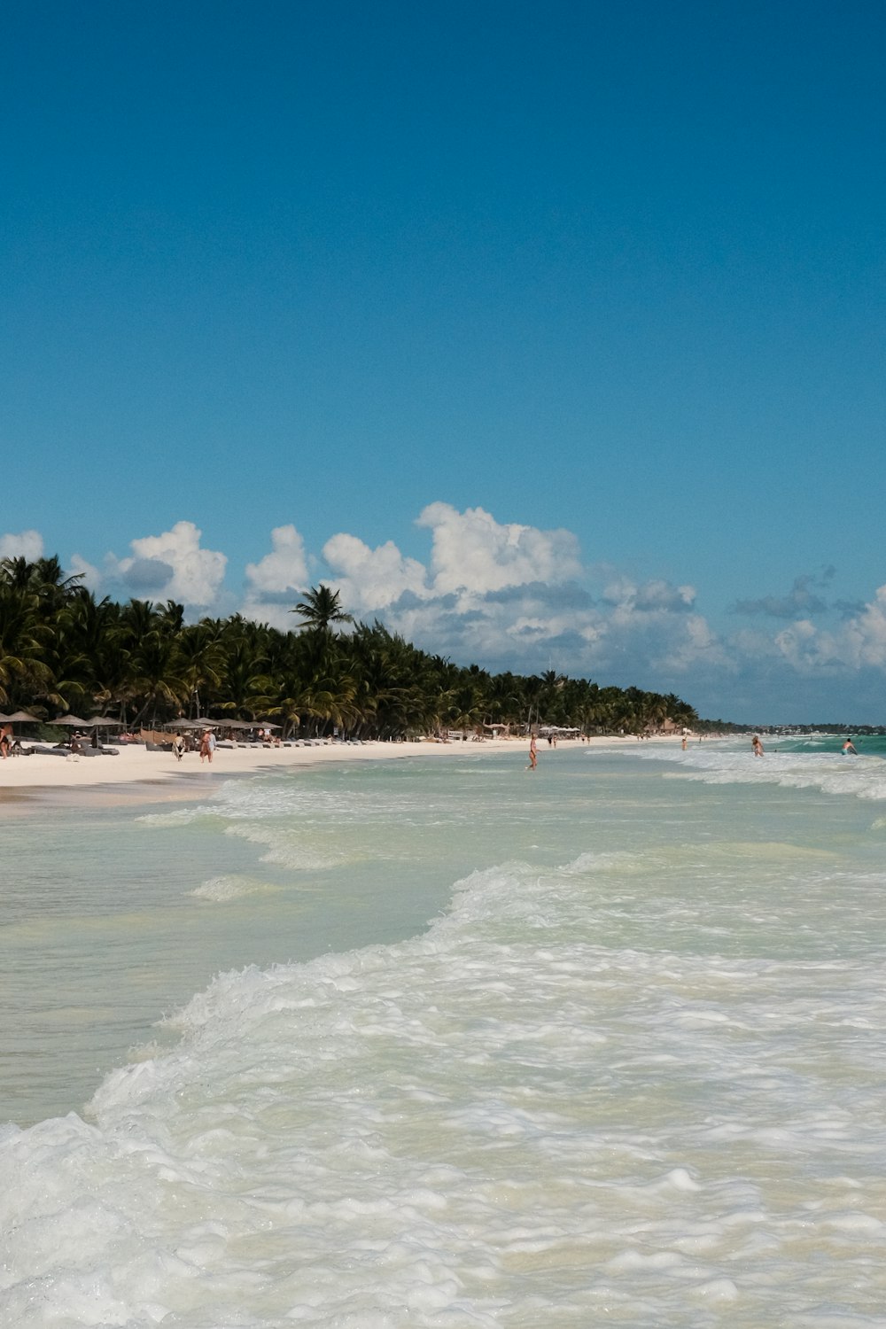 a beach with people walking in the water