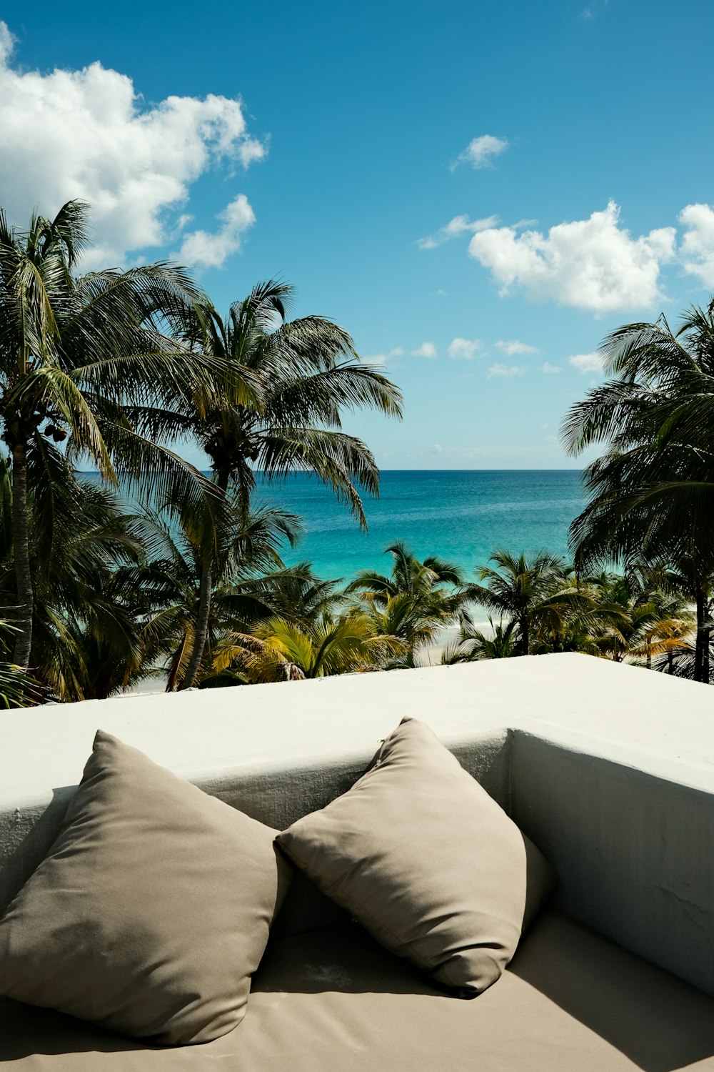 a couch with two pillows on top of it in front of the ocean