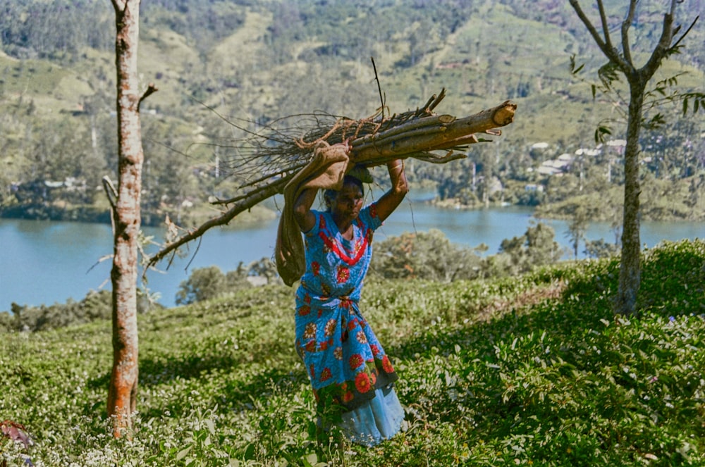 a woman carrying a large tree branch over her head