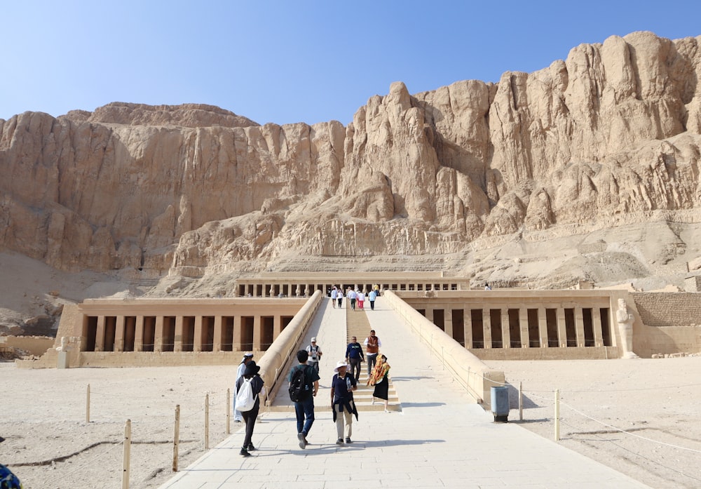 a group of people walking across a bridge in front of a mountain