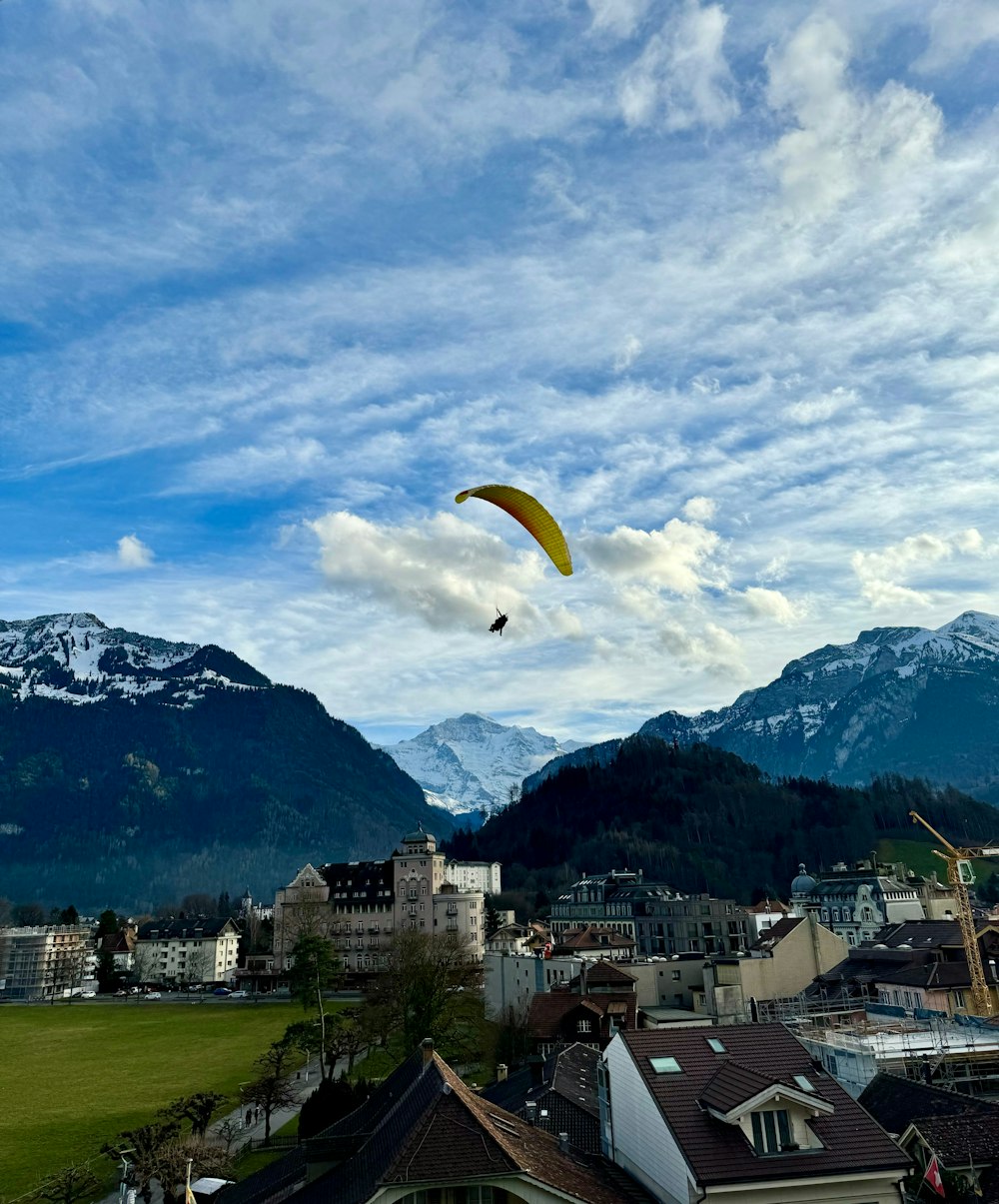 a kite flying over a city with mountains in the background