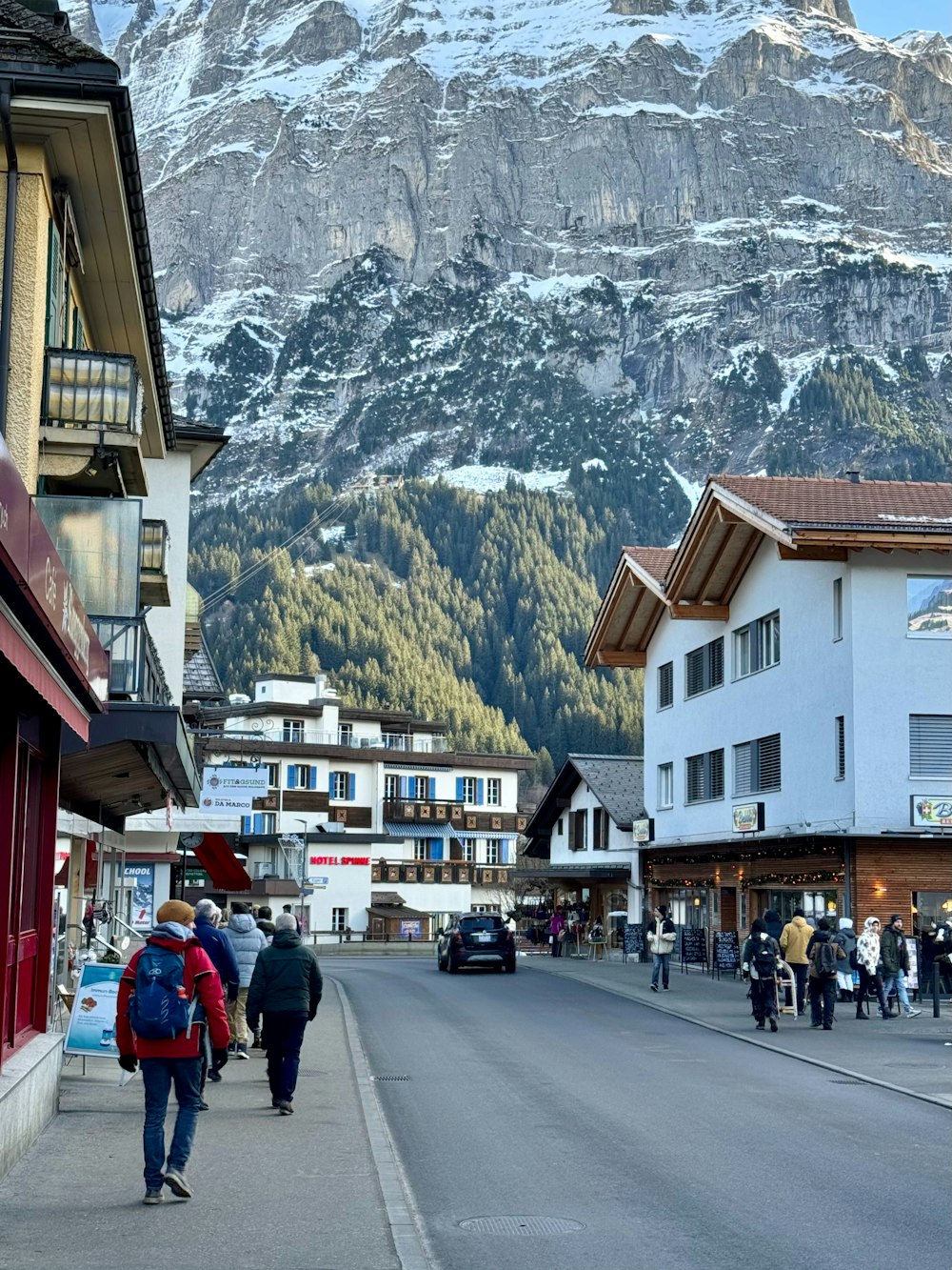 a group of people walking down a street next to a mountain