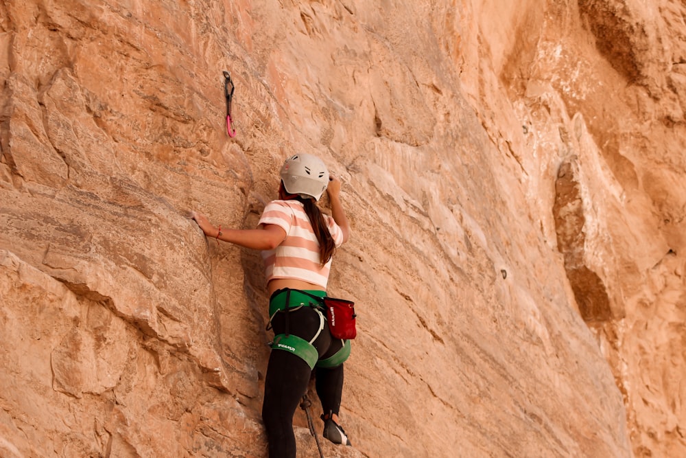 a woman climbing up the side of a mountain