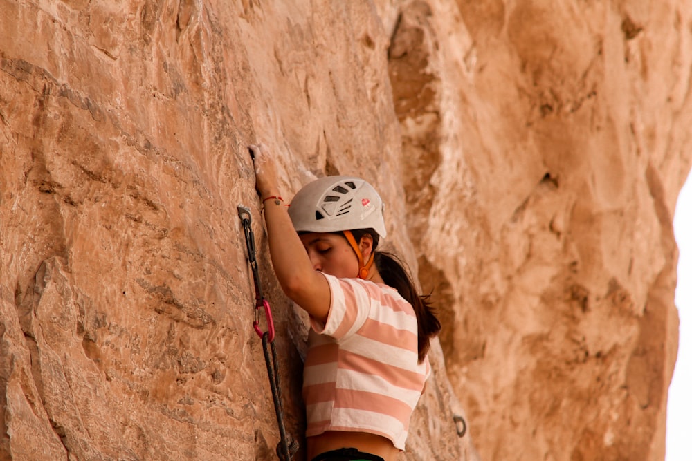 a woman climbing up the side of a mountain