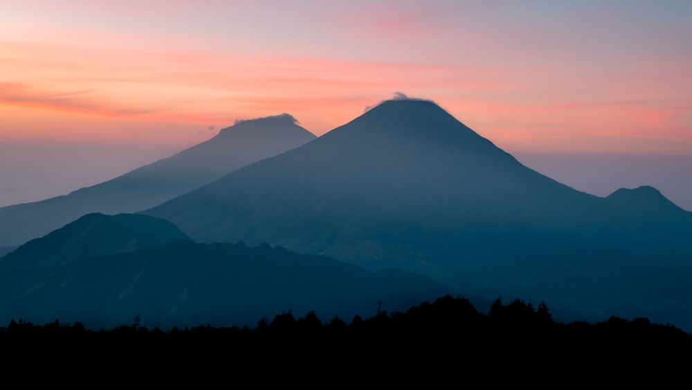 une montagne avec un ciel rose et bleu en arrière-plan