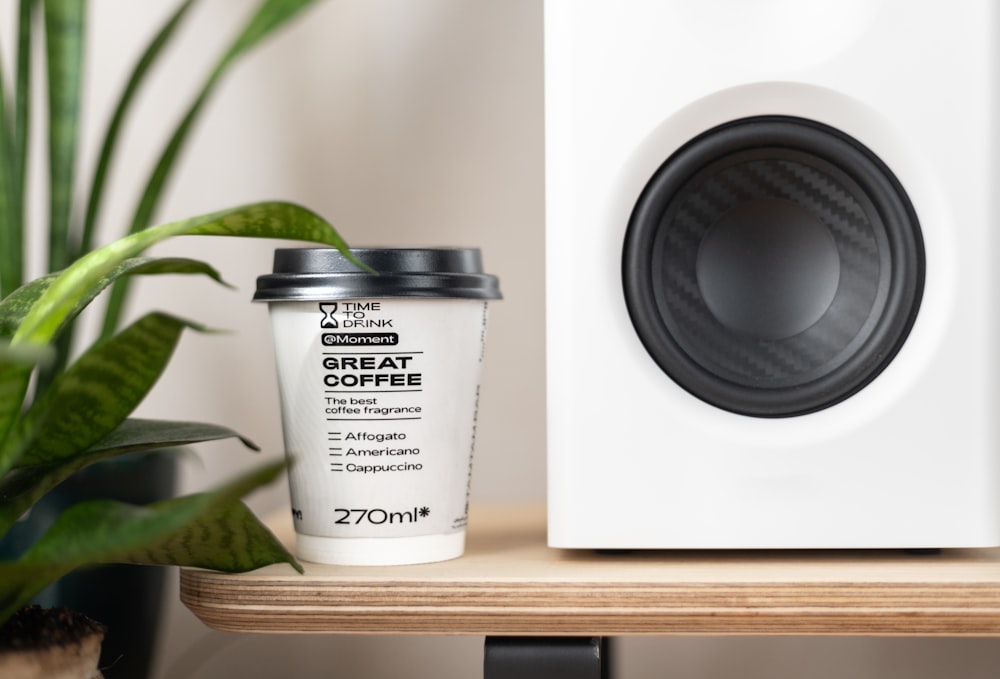 a cup of coffee sitting next to a speaker